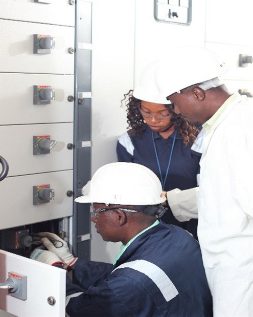 Trainees working inside a low-voltage switchgear panel with an instructor