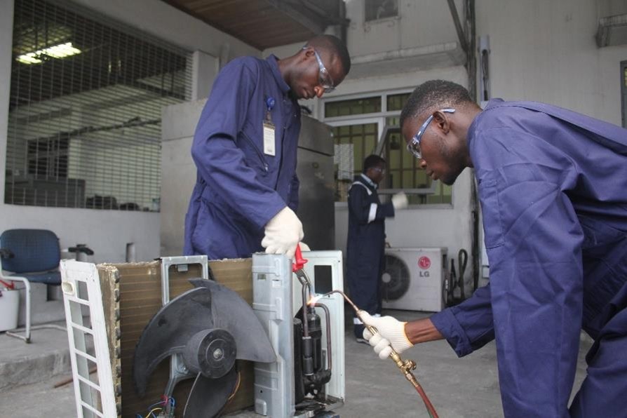 Trainees brazing refrigerant pipework on a split-unit condenser
